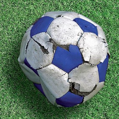 Auf grünem Rasen liegt ein kaputter Fußball. Darunter als Text "Foul Play"