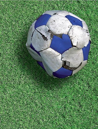 Auf grünem Rasen liegt ein kaputter Fußball. Darunter als Text "Foul Play"