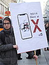 Ein Südwind-Aktivist hält vor einem Apple-Store ein den Konzern kritisierendes Schild hoch
