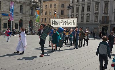 Jugendgruppe Graz bei einem öffentlichen Auftritt mit Banner und Verkleidungen