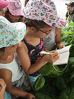 Kinder tragen beim Geocaching Informationen in einen Block ein