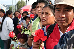 ArbeiterInnen in Ecuador halten rote Rosen in den Händen