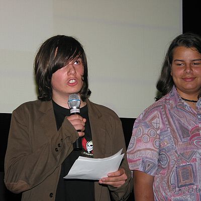 Zwei Schüler auf der Bühne beim Südwind Filmpreis. Einer von beiden spricht ins Mikrofon 
