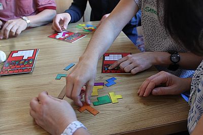 Sustainable Development Goals Spiel. Menschen sitzen bei einem Tisch und spielen