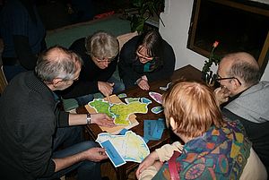 Mehrere Erwachsene rätseln zusammen an einer Aufgabe