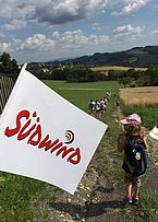 Südwind Fahne beim Geocaching, im Hintergrund Kinder und Jugendliche auf einer Wiese